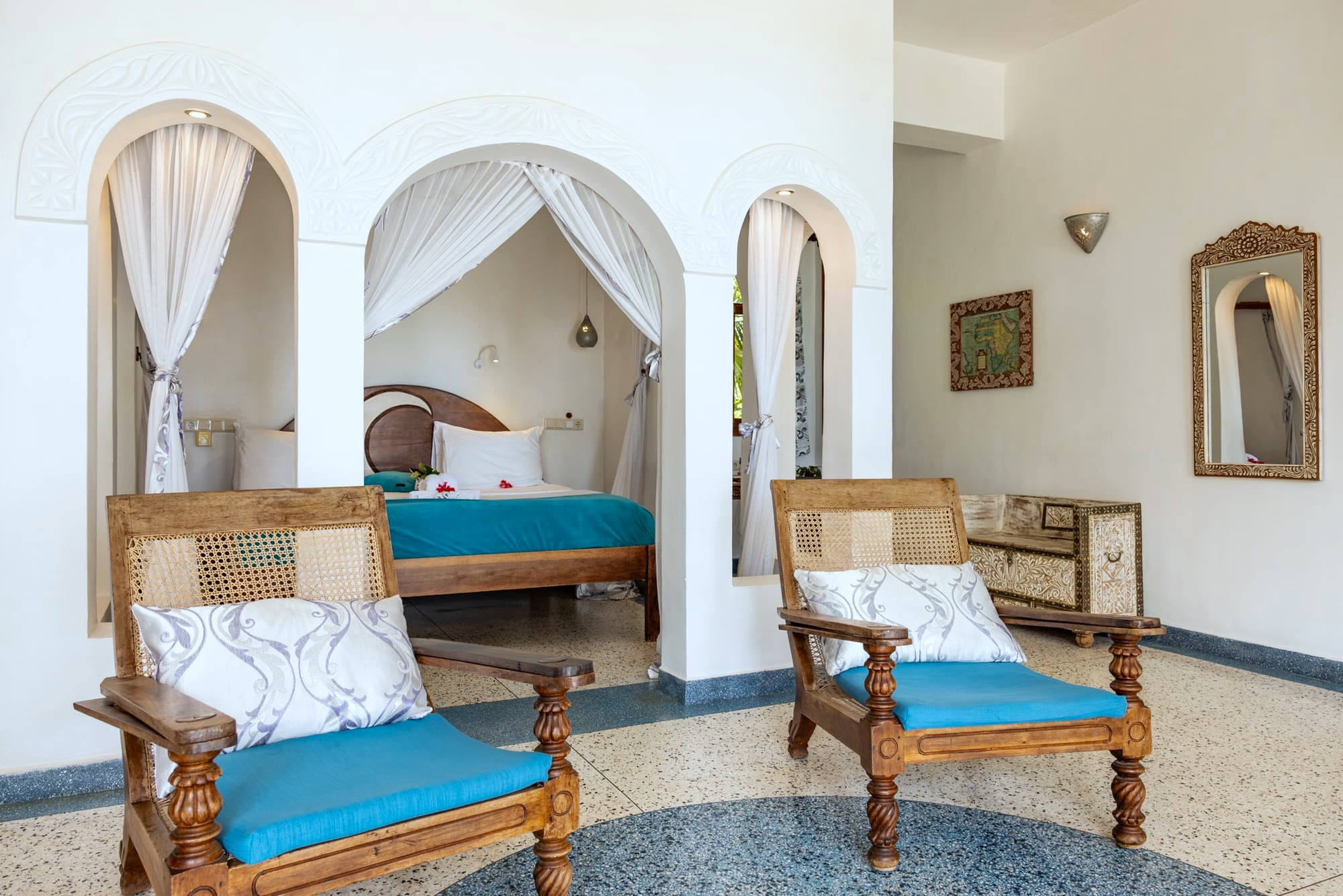 Mwezi: a canopy bed and a seating corner against white walls