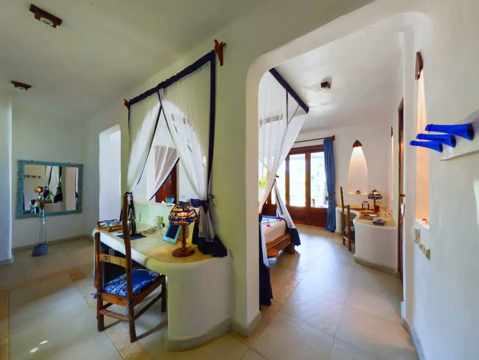 Room Maji interior at Asili House, Boutique Hotel Matlai Zanzibar, showing handcrafted décor including blue bottle cloth holders and recycled-oil candles.