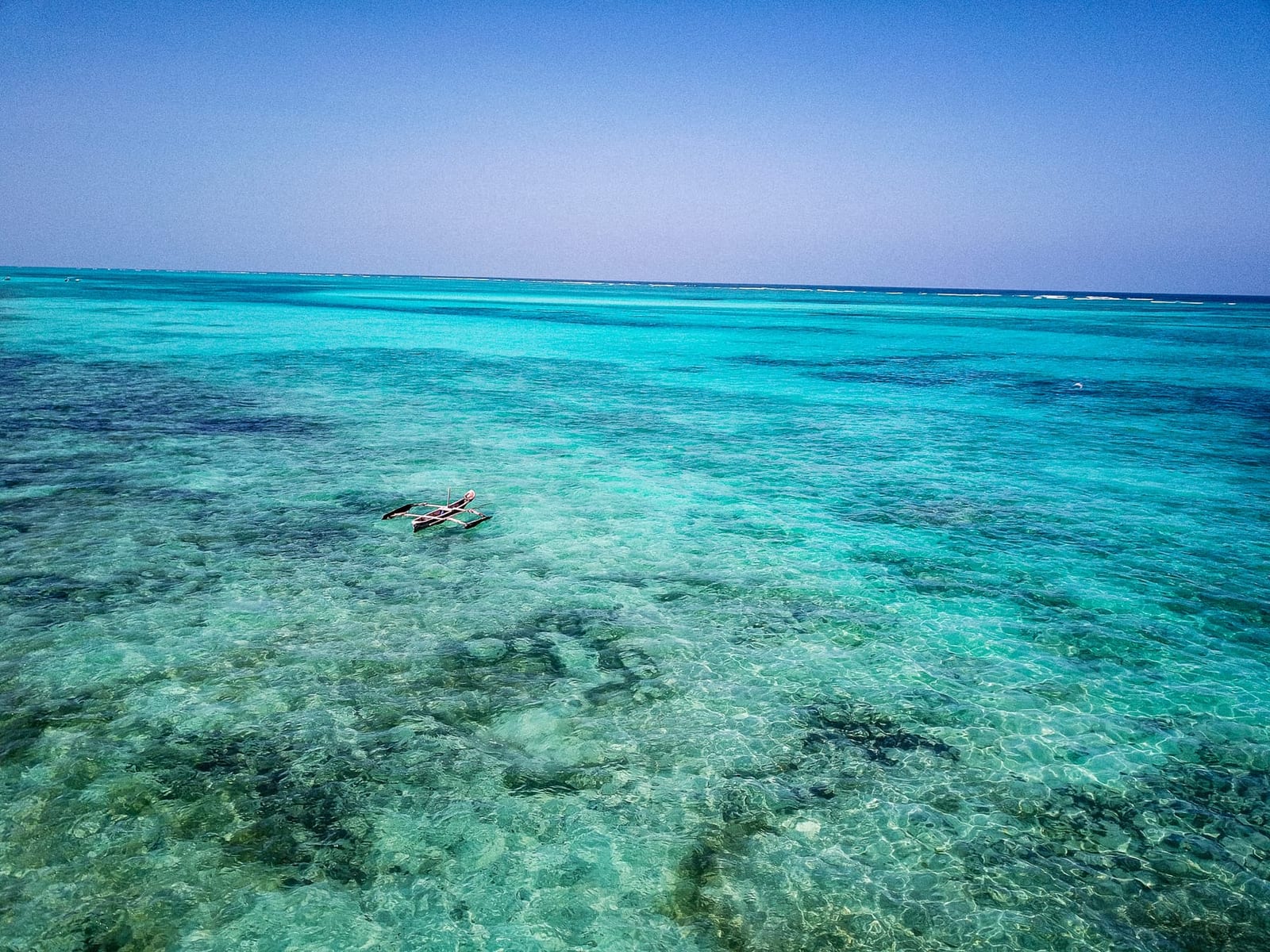 Aerial view of a traditional wooden fishing boat on clear turquoise water off Michamvi Pingwe